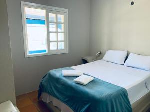 a bedroom with a bed with two towels on it at Pousada Portal da Praia in Capão da Canoa