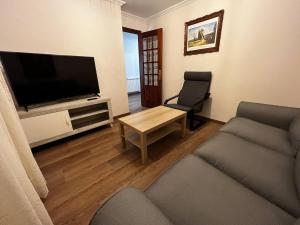 a living room with a tv and a couch and a table at Castiñeiras Street in Sarria