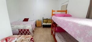 a room with two beds in a room at KITNET S1 em TORRES-RS - Na mais bela praia Gaúcha - Cozinha - Banheiro - Ar condicionado - TV e Wi-Fi - Estacionamento - Acomoda até 5 pessoas - Anfitriã Superhost no BnB in Torres