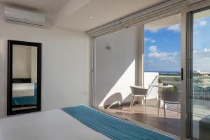 a bedroom with a bed and a balcony with a table at Suites Malecon Cancun in Cancún