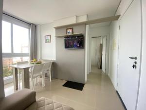 sala de estar con mesa y TV en la pared en Apartamento com vista para o mar en Capão da Canoa
