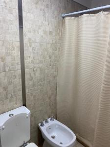 y baño con aseo y cortina de ducha. en Departamento Céntrico II en Salta