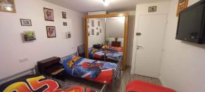 um quarto com 2 camas individuais e uma televisão em Les villégiatures de Muse em Saint-Marcouf