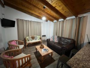 uma sala de estar com um sofá de couro e cadeiras em Casa Azul em Santa Rosa de Calamuchita