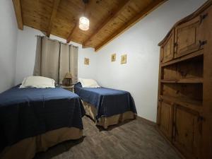 two beds in a room with wooden ceilings at Casa Azul in Santa Rosa de Calamuchita