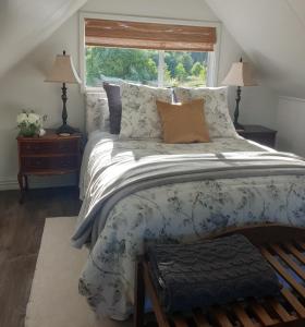 ein Schlafzimmer mit einem großen Bett und einem Fenster in der Unterkunft Blue Bell Cottage. Serene luxury farmstead in Lower Moutere