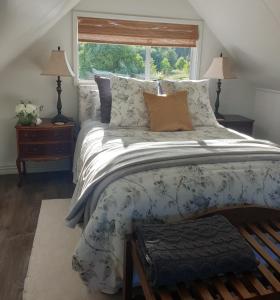 ein Schlafzimmer mit großem Bett und Fenster in der Unterkunft Blue Bell Cottage. Serene luxury farmstead in Lower Moutere