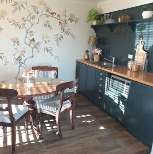 a kitchen with a wooden table and chairs and a table and a counter at Blue Bell Cottage. Serene luxury farmstead in Lower Moutere