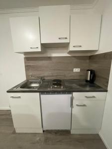 a small kitchen with white cabinets and a sink at Giulias Budget Haus in Reutte