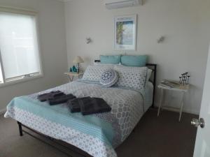 a bedroom with a bed with blue and white sheets and pillows at Grey Goose @ Smiths in Smiths Beach