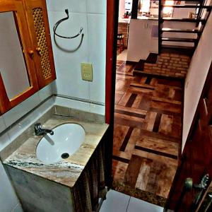 ein Bad mit einem Waschbecken und einen Flur mit einer Treppe in der Unterkunft ALUGO CASA INTEIRA 3 SUÎTES EXCELENTE CASA no centro de Cabo Frio in Cabo Frio