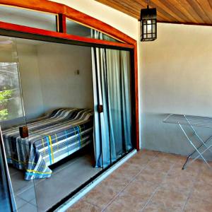 Schlafzimmer mit einem Bett und einer Glasschiebetür in der Unterkunft ALUGO CASA INTEIRA 3 SUÎTES EXCELENTE CASA no centro de Cabo Frio in Cabo Frio