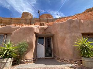a house with a large rock wall with a door at 894 Holly Court in Coober Pedy