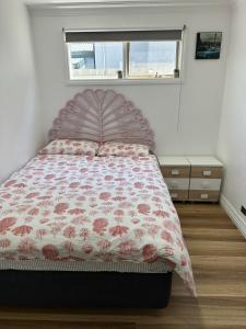 a bedroom with a bed with a floral bedspread and a window at Oakleigh Private unit in Oakleigh