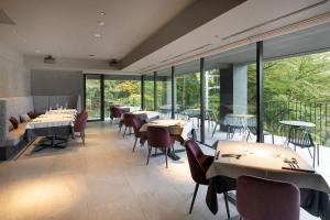 a restaurant with tables and chairs and large windows at HAKONE NICA in Hakone