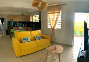 un soggiorno con divano giallo e tavolo di Superbe Appart T2 de standing, à l'Anse à l'âne, à 5mn à pied des plages a Les Trois-Îlets
