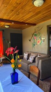 ein Wohnzimmer mit einem Sofa und einem Tisch mit Blumen in der Unterkunft Lidia's Mountain View Vacation Homes in Monteverde Costa Rica