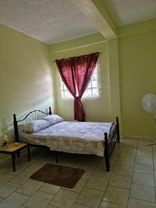 sypialnia z łóżkiem i oknem z czerwoną zasłoną w obiekcie Coco Rose Apartments w mieście Soufrière