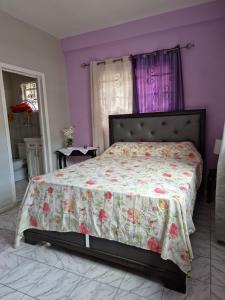 sypialnia z łóżkiem z narzutą kwiatową w obiekcie Coco Rose Apartments w mieście Soufrière
