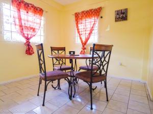 a dining room with a table and four chairs at Coco Rose Apartments in Soufrière