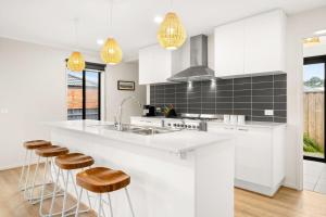 eine Küche mit weißen Schränken und einer Theke mit Stühlen in der Unterkunft Kookaburra Corner in Cowes