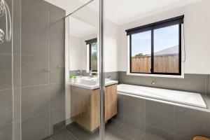 ein Badezimmer mit Badewanne und Waschbecken und einem Fenster in der Unterkunft Kookaburra Corner in Cowes + 12 Fotos