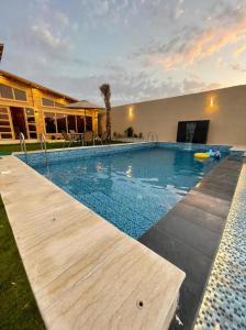 a swimming pool with a wooden deck next to a house at شاليهات ريموندا الريفيه الطائف in Taif