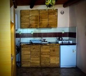 cocina con armarios de madera y nevera blanca en La CUEVA DEL OSO en San Rafael