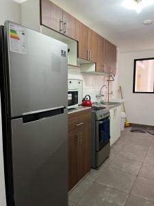 a kitchen with a stainless steel refrigerator and wooden cabinets at Moderno y acogedor apartamento en el mágico Cusco in Cusco