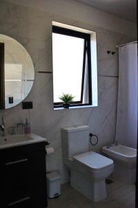 a bathroom with a toilet and a sink and a window at Mendoza Relax & Comfort in Mendoza