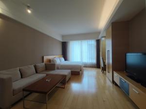 a living room with a couch and a bed and a television at Tianjin Crown International Apartment in Tianjin
