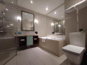 a bathroom with a toilet and a tub and a sink at Tianjin Crown International Apartment in Tianjin