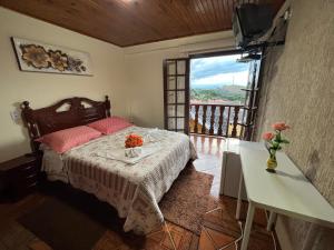 a bedroom with a bed with a table and a window at Pousada Heron in Campos do Jordão