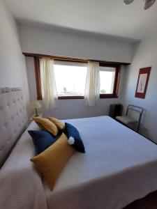Un dormitorio con una cama con almohadas azules y una ventana en Departamento en Varese frente al mar en Mar del Plata