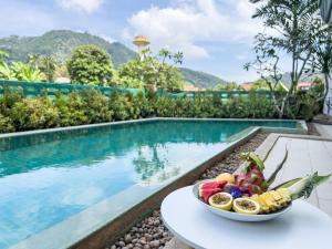 a bowl of fruit on a table next to a swimming pool at Melissa Kata Beach Resort in Kata Beach