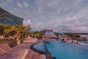 a swimming pool with lounge chairs and umbrellas at Dream Beach Huts in Nusa Lembongan