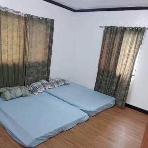 - 2 lits dans une chambre dotée de rideaux et de parquet dans l'établissement Lilia's Garden Home, à Tagaytay