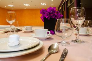 einen Tisch mit Tellern, Weingläsern und lila Blumen in der Unterkunft Hotel del Valle Inn in Pachuca de Soto