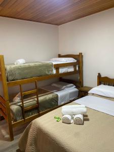 a room with three bunk beds and towels on a bed at Hospedagem Casa Lorenzi 2 in Urubici