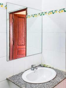 a bathroom sink with a mirror and a red door at Bountang Mountain View Riverside Hotel in Vang Vieng