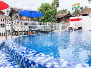 a swimming pool with a blue and white tile floor and umbrella at Bountang Mountain View Riverside Hotel in Vang Vieng