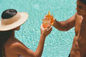 two women holding a drink next to a pool at Wayfinder Waikiki in Honolulu