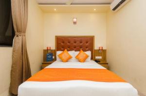 a bedroom with a large bed with orange pillows at Aster Hotel Near Mumbai Airport in Mumbai