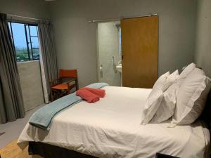 a bedroom with a white bed with a red towel on it at Whinstone Farm in Greytown