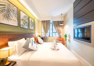 a bedroom with a large white bed and a flat screen tv at Greystone Centrestage PJ in Petaling Jaya