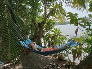 アンバランゴダにあるLake Life Villaの水面横のハンモックに横たわる男