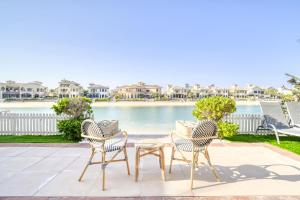 - un groupe de chaises et une table en face d'une piscine dans l'établissement Stella Stays Brilliant 4 BDR Palm Villa Beach Private Pool, à Dubaï