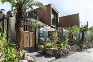 une maison avec des palmiers et une clôture avec un parasol dans l'établissement Deer Chaser Hotel, à Yuchi