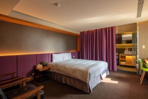 ein Schlafzimmer mit einem Bett und einer lila Wand in der Unterkunft Goodmore Hotel in Taipeh