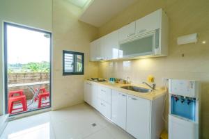 a kitchen with white cabinets and a sink and a window at Qingyun Homestay in Toucheng